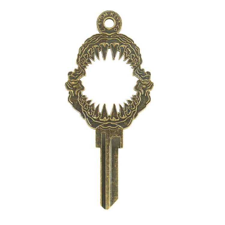 Gold key on white background with shark mouth design.