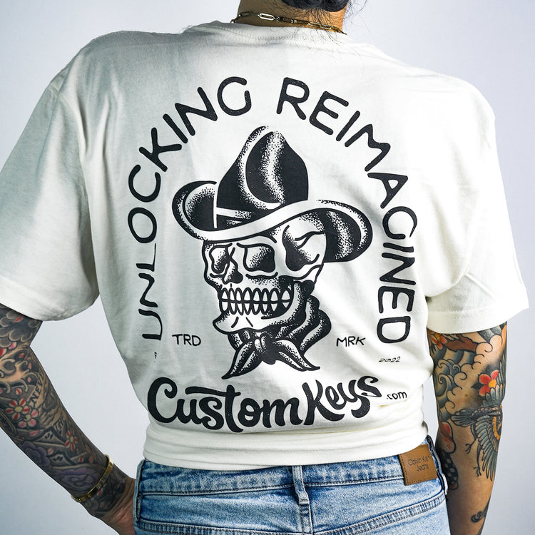 Tattooed woman wearing a white t-shirt with skull with cowboy hat and 'CustomKeys.com' text on a white background