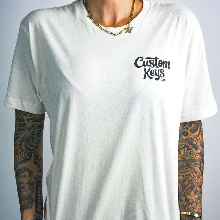 Tattooed woman wearing a white t-shirt with 'Custom Keys.com' text on a white background