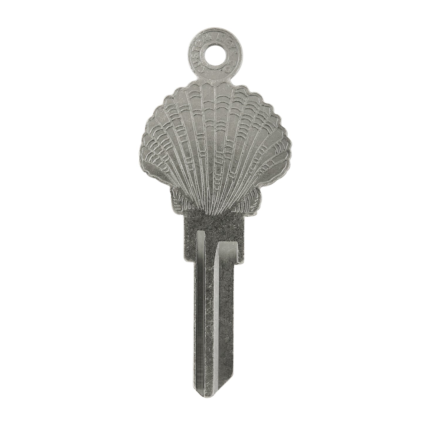 Silver key on white background with seashell design.