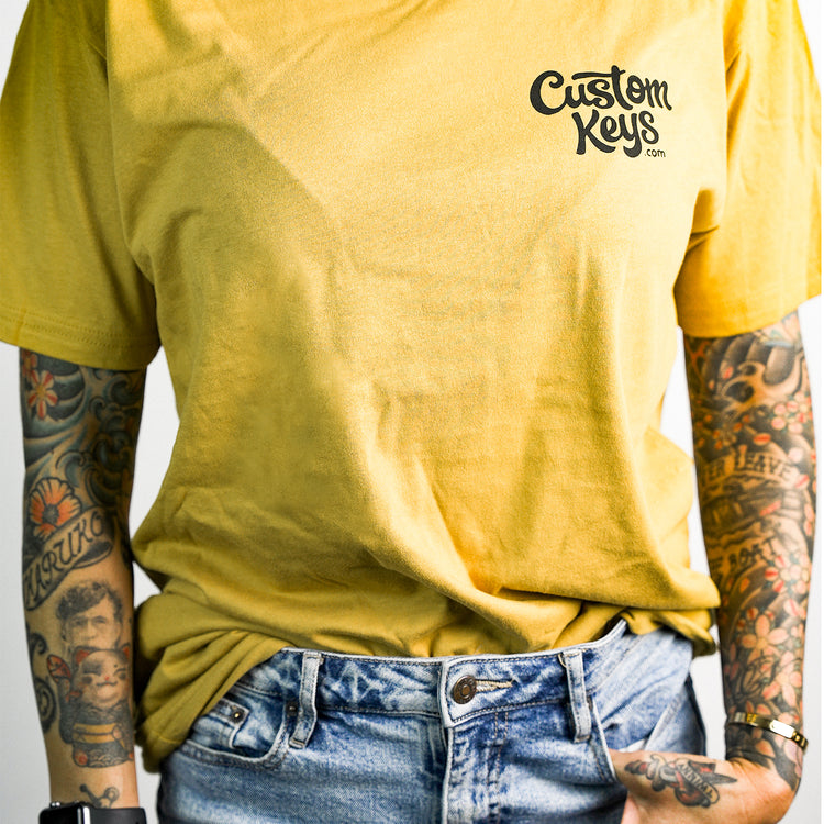 Tattooed woman wearing a yellow t-shirt with 'Custom Keys.com' text on a white background