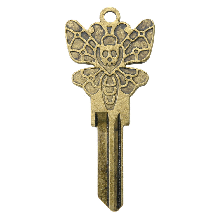 Brass key on white background with death moth design.